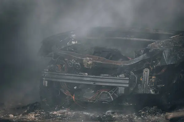 İtfaiyeciler yanan bir arabayı garajda söndürür. Yanmış araba. Kurtarıcılar. Sağlam duman. Acil durum. Sigorta davası.