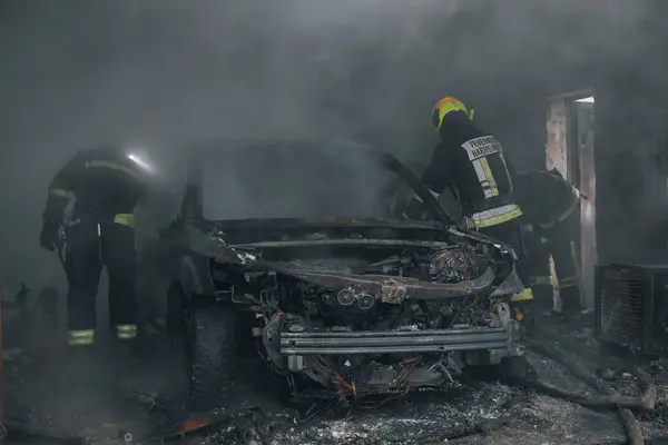 消防员在车库里扑灭了一辆着火的汽车 燃烧的车 救援人员 紧急情况 保险案件 免版税图库照片