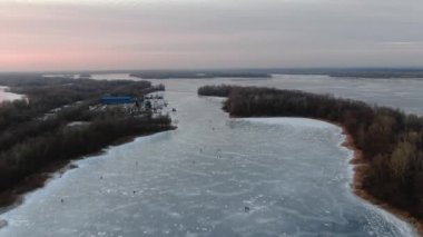 Buz kaplı nehri olan güzel bir kış nehri manzarası. Buzda kış balıkçılığı. Balıkçı ya da olta atan balıkçı. Hava aracı görüntüsü. Göl, kar. Kışın açık hava eğlencesi