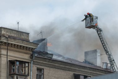 Kurtarma ekipleri yangını söndürüyor. Büyük bir roket saldırısından sonra hasar görmüş bir yerleşim yeri. Çok duman var. Ev yanıyor..