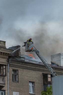 Kurtarma ekipleri yangını söndürüyor. Büyük bir roket saldırısından sonra hasar görmüş bir yerleşim yeri. Çok duman var. Ev yanıyor..