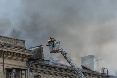 Kurtarma ekipleri yangını söndürüyor. Büyük bir roket saldırısından sonra hasar görmüş bir yerleşim yeri. Çok duman var. Ev yanıyor..