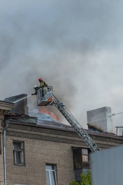 Kurtarma ekipleri yangını söndürüyor. Büyük bir roket saldırısından sonra hasar görmüş bir yerleşim yeri. Çok duman var. Ev yanıyor..