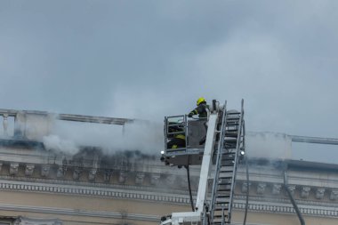 Kurtarma ekipleri yangını söndürüyor. Büyük bir roket saldırısından sonra hasar görmüş bir yerleşim yeri. Çok duman var. Ev yanıyor..