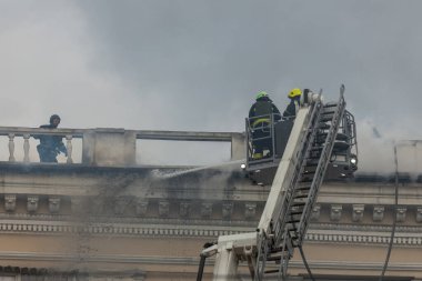 Kurtarma ekipleri yangını söndürüyor. Büyük bir roket saldırısından sonra hasar görmüş bir yerleşim yeri. Çok duman var. Ev yanıyor..