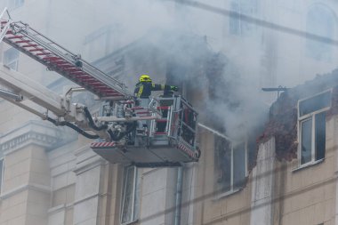 Kurtarma ekipleri yangını söndürüyor. Büyük bir roket saldırısından sonra hasar görmüş bir yerleşim yeri. Çok duman var. Ev yanıyor..