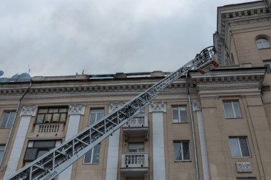 Kurtarma ekipleri yangını söndürüyor. Büyük bir roket saldırısından sonra hasar görmüş bir yerleşim yeri. Çok duman var. Ev yanıyor..