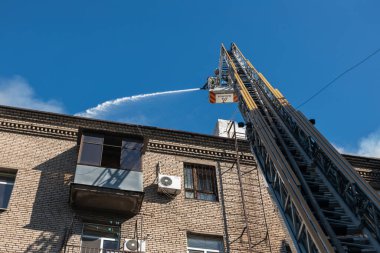 Kurtarma ekipleri yangını söndürüyor. Büyük bir roket saldırısından sonra hasar görmüş bir yerleşim yeri. Çok duman var. Ev yanıyor..
