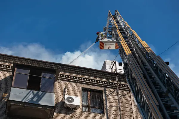 Kurtarma ekipleri yangını söndürüyor. Büyük bir roket saldırısından sonra hasar görmüş bir yerleşim yeri. Çok duman var. Ev yanıyor..