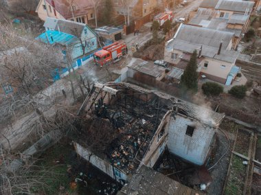 Yanmış bir evin üst manzarası. Ev tamamen yangın tarafından tahrip edildi. Çatı çöktü, duvarlar siyaha döndü. Yanmış eşyalar evin etrafına saçılmış. Özel bir evde yangın.