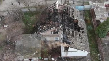 Yanmış bir evin üst manzarası. Ev tamamen yangın tarafından tahrip edildi. Çatı çöktü, duvarlar siyaha döndü. Yanmış eşyalar evin etrafına saçılmış. Özel bir evde yangın.