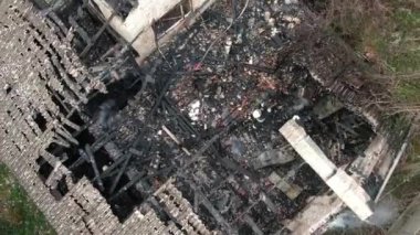 Yanmış bir evin üst manzarası. Ev tamamen yangın tarafından tahrip edildi. Çatı çöktü, duvarlar siyaha döndü. Yanmış eşyalar evin etrafına saçılmış. Özel bir evde yangın.