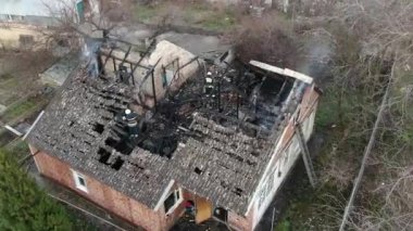 Yanmış bir evin üst manzarası. Ev tamamen yangın tarafından tahrip edildi. Çatı çöktü, duvarlar siyaha döndü. Yanmış eşyalar evin etrafına saçılmış. Özel bir evde yangın.