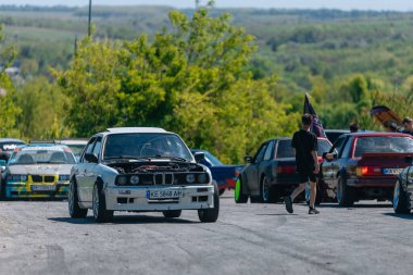Bir yarış arabası hızlı bir şekilde sürüklenir. Sürücü arabayı sürüklüyor. Arka planda dumanla savrulan bir araba, dumanlı tekerlekler. Hız. Ekstrem spor. Rotadan. DNIPRO, UKRAINE - 25 Mayıs 2024