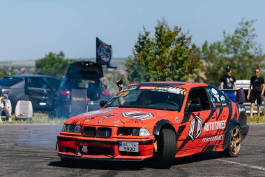 Bir yarış arabası hızlı bir şekilde sürüklenir. Sürücü arabayı sürüklüyor. Arka planda dumanla savrulan bir araba, dumanlı tekerlekler. Hız. Ekstrem spor. Rotadan. DNIPRO, UKRAINE - 25 Mayıs 2024