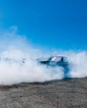 Bir yarış arabası hızlı bir şekilde sürüklenir. Sürücü arabayı sürüklüyor. Arka planda dumanla savrulan bir araba, dumanlı tekerlekler. Hız. Ekstrem spor. Rotadan. DNIPRO, UKRAINE - 25 Mayıs 2024