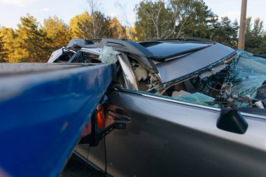 Otoyolda bir araba çarpıştı. Ciddi bir kaza. Yoldaki trafik kazaları. Kırık ön cam. Araba bir kamyonun karavanının altında uçtu. Trafik sıkışık. Sigorta davası yolda.