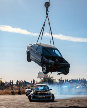 Bir yarış arabası hızlı bir şekilde sürüklenir. Sürücü arabayı sürüklüyor. Arka planda dumanla savrulan bir araba, dumanlı tekerlekler. Hız. Ekstrem spor. Yönlendirme. 