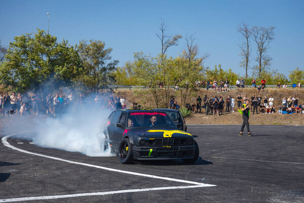 A racing car drifts on a fast track. The driver drifts the car. A car skidding against a background of smoke, smoking wheels. Speed. Extremesport. Route. 