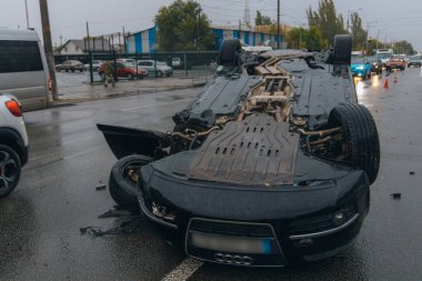 Araba kaygan yol nedeniyle devrildi. Yağmurdan sonra. Araba kontrolden çıkmış bir şekilde çatısına iniyor. Trafik kazası. Arabada ağır hasar var. Ayrıntıları kapat..