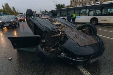 Araba kaygan yol nedeniyle devrildi. Yağmurdan sonra. Araba kontrolden çıkmış bir şekilde çatısına iniyor. Trafik kazası. Arabada ağır hasar var. Ayrıntıları kapat..