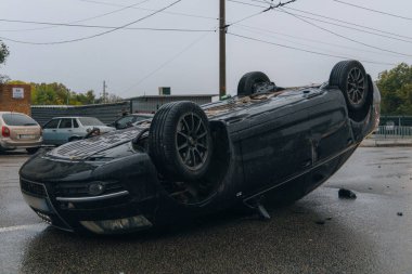 Araba kaygan yol nedeniyle devrildi. Yağmurdan sonra. Araba kontrolden çıkmış bir şekilde çatısına iniyor. Trafik kazası. Arabada ağır hasar var. Ayrıntıları kapat..