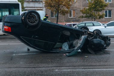 Araba kaygan yol nedeniyle devrildi. Yağmurdan sonra. Araba kontrolden çıkmış bir şekilde çatısına iniyor. Trafik kazası. Arabada ağır hasar var. Ayrıntıları kapat..