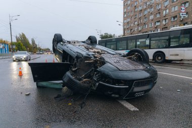 Araba kaygan yol nedeniyle devrildi. Yağmurdan sonra. Araba kontrolden çıkmış bir şekilde çatısına iniyor. Trafik kazası. Arabada ağır hasar var. Ayrıntıları kapat..