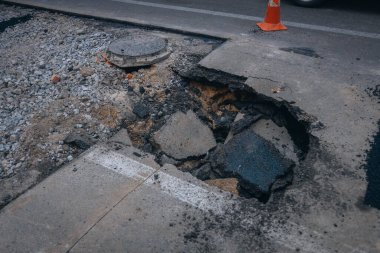 A big hole in the concrete floor. A huge hole in the road. Dangerous for traffic. ra in the ground in the middle of the road. Asphalt that has fallen into the ground clipart