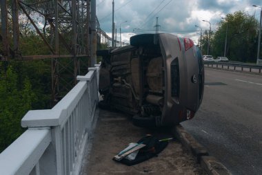 Trafik kazası. Otobanda devrilmiş bir araba. Arabada ağır hasar var. Detaylar, yakın plan. Araba yan yatar..