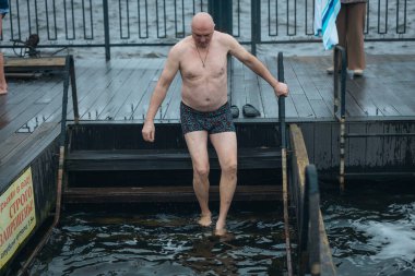 Ukrayna 'da kış tespihi. Epifani banyosu bir halk geleneğidir. Buzlu suya daldırmak. Ortodoks ayini buz deliğinde banyo yapmak. Birçok insan banyo yapar..