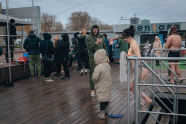 Ukrayna 'da kış tespihi. Epifani banyosu bir halk geleneğidir. Buzlu suya daldırmak. Ortodoks ayini buz deliğinde banyo yapmak. Birçok insan banyo yapar..