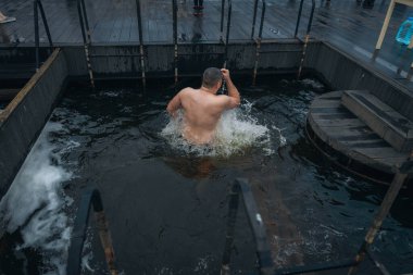 Ukrayna 'da kış tespihi. Epifani banyosu bir halk geleneğidir. Buzlu suya daldırmak. Ortodoks ayini buz deliğinde banyo yapmak. Birçok insan banyo yapar..
