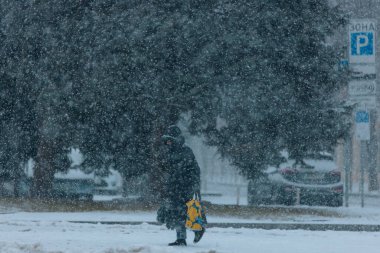 Winter Park 'ta. Şiddetli kar yağışı sırasında şehirde dolaşmak. Ukrayna 'da kış manzarası. Şehir parkında beyaz kar. Soğuk hava, yılın bu zamanı. Şehir caddesinde karla kaplı bir yer. Dinyester şehri