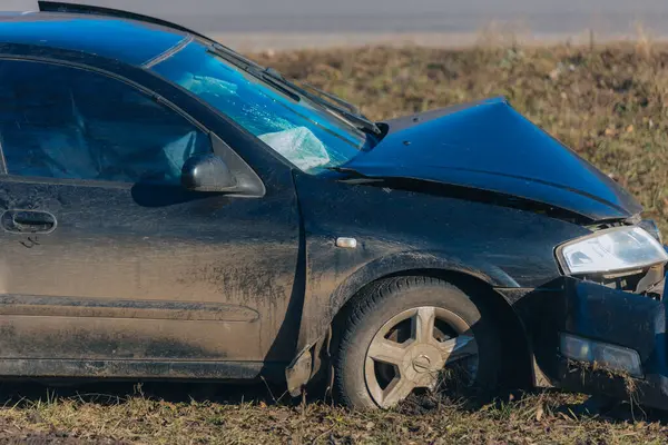 Yolun kenarındaki bir kazadan sonra araba, yakın plan. Ön tarafında ciddi hasar olan siyah bir araba kaza mahallinde. Yolun kenarındaki bir kazadan sonra araba. Kazaydı.
