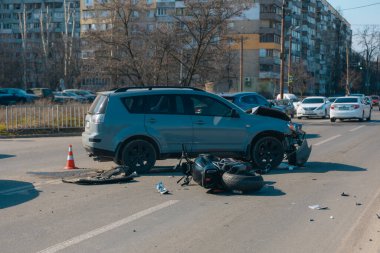 Kazadan sonra kaza yapmış bir motosiklet ve hasarlı bir araba, yakın plan. Yolda bir motosiklet ve ciddi hasar görmüş bir çapraz yol var. Çarpışmadan sonra....