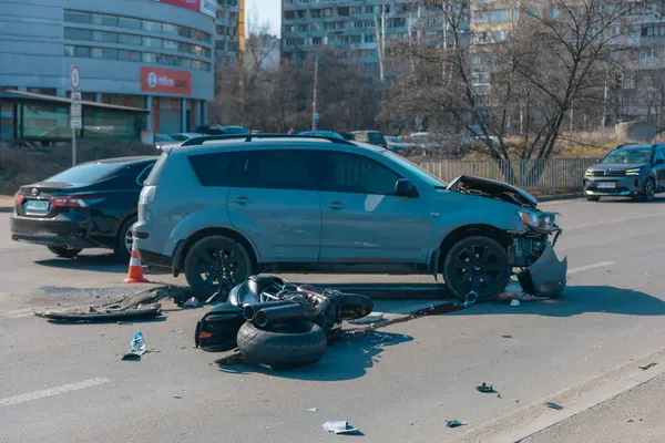 Kazadan sonra kaza yapmış bir motosiklet ve hasarlı bir araba, yakın plan. Yolda bir motosiklet ve ciddi hasar görmüş bir çapraz yol var. Çarpışmadan sonra....