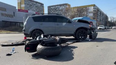 Kazadan sonra kaza yapmış bir motosiklet ve hasarlı bir araba, yakın plan. Yolda bir motosiklet ve ciddi hasar görmüş bir çapraz yol var. Çarpışmadan sonra.... 