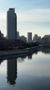 Cityscape with river and buildings reflected, panoramic view. Silhouettes of buildings are visible against the sky. Ukrainian city of Dnepr