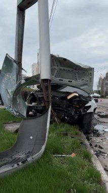 Şehir yolundaki bir kazadan sonra ağır hasar görmüş beyaz bir sedan. Araba bir direğe çarptı, ön kısmı parçalandı, kaput açık. Kaza, yol tehlikesi ve sigorta kavramı.