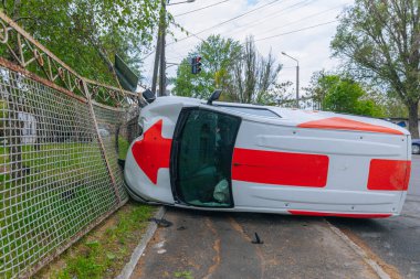 Devrilmiş bir araba yolun kenarında yan yatar. Bir araba kazasının olduğu yer. Arabada ciddi hasar var. Detaylar, yakın plan. Bir direğe çarpmış..