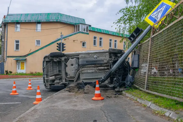 Devrilmiş bir araba yolun kenarında yan yatar. Bir araba kazasının olduğu yer. Arabada ciddi hasar var. Detaylar, yakın plan. Bir direğe çarpmış..