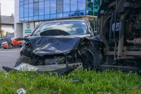 Bir şehir caddesinde iki arabalık bir kaza meydana geldi, bunlardan biri devrildi. Kırık farlar, yamuk bir kaput, kırık bir tampon ve cam kırıkları görülebilir.. 