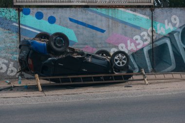 Olay yeri: Bir kazadan sonra yolun kenarında devrilmiş bir araba. Araba baş aşağı duruyor. Çarpışma sonrasını. Ayrıntıları kapat..