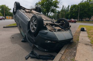 Olay yeri: Bir kazadan sonra yolun kenarında devrilmiş bir araba. Araba baş aşağı duruyor. Çarpışma sonrasını. Ayrıntıları kapat..