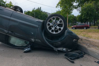 Olay yeri: Bir kazadan sonra yolun kenarında devrilmiş bir araba. Araba baş aşağı duruyor. Çarpışma sonrasını. Ayrıntıları kapat..