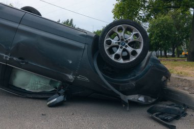 Olay yeri: Bir kazadan sonra yolun kenarında devrilmiş bir araba. Araba baş aşağı duruyor. Çarpışma sonrasını. Ayrıntıları kapat..