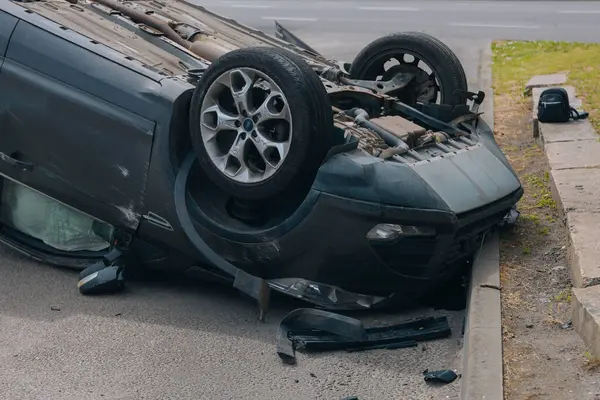 Olay yeri: Bir kazadan sonra yolun kenarında devrilmiş bir araba. Araba baş aşağı duruyor. Çarpışma sonrasını. Ayrıntıları kapat..