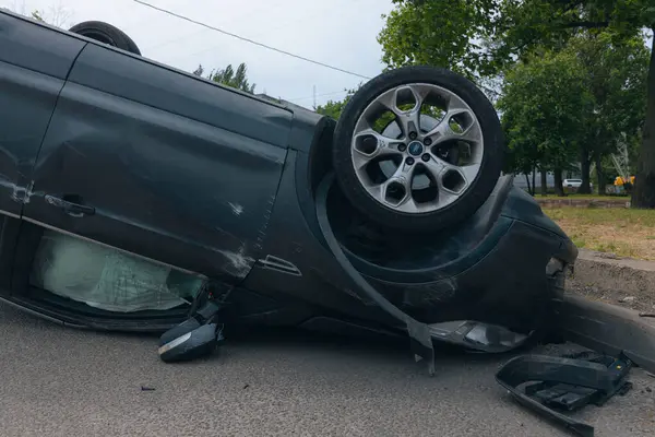 Olay yeri: Bir kazadan sonra yolun kenarında devrilmiş bir araba. Araba baş aşağı duruyor. Çarpışma sonrasını. Ayrıntıları kapat..
