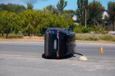 Kaza hasarı: yolda devrilmiş bir arabanın görüntüsü. Devrilen araba yan yatar. Çarpışma sonrası oluşmuş. Detaylar, yakın plan. Kazalar, sigorta ve güvenlik konuları.
